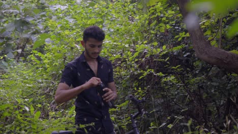 boy-man-walking-with-a-cycle-in-deep-jungle-slow-motion-drinking-water-mid-shot