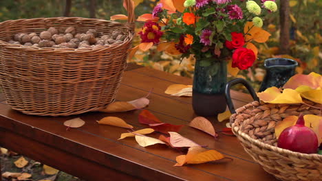 large wicker basket full of walnuts next to vase of flowers next to basket bowl of red pomegranates