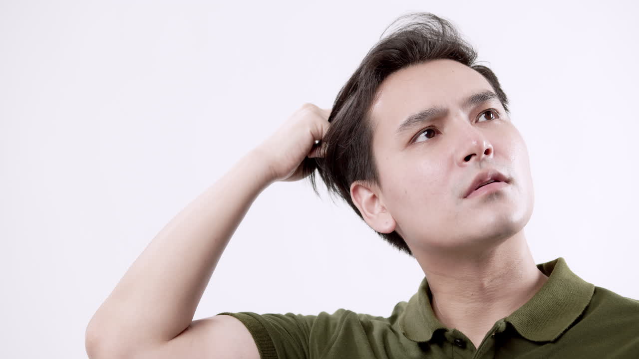 A young male combing his hair using his fingers notices his hair loss.