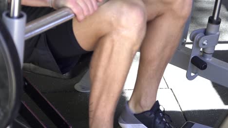 muscly man in home gym exercising smith machine barbell calf raise workout