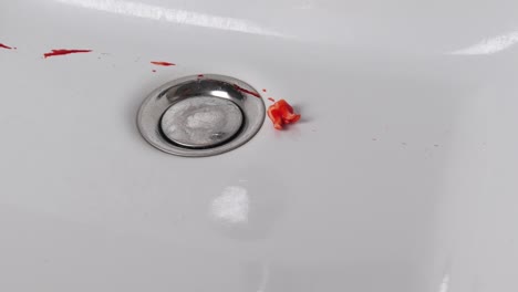 Bloody-tooth-falls-into-white-sink.-Close-up