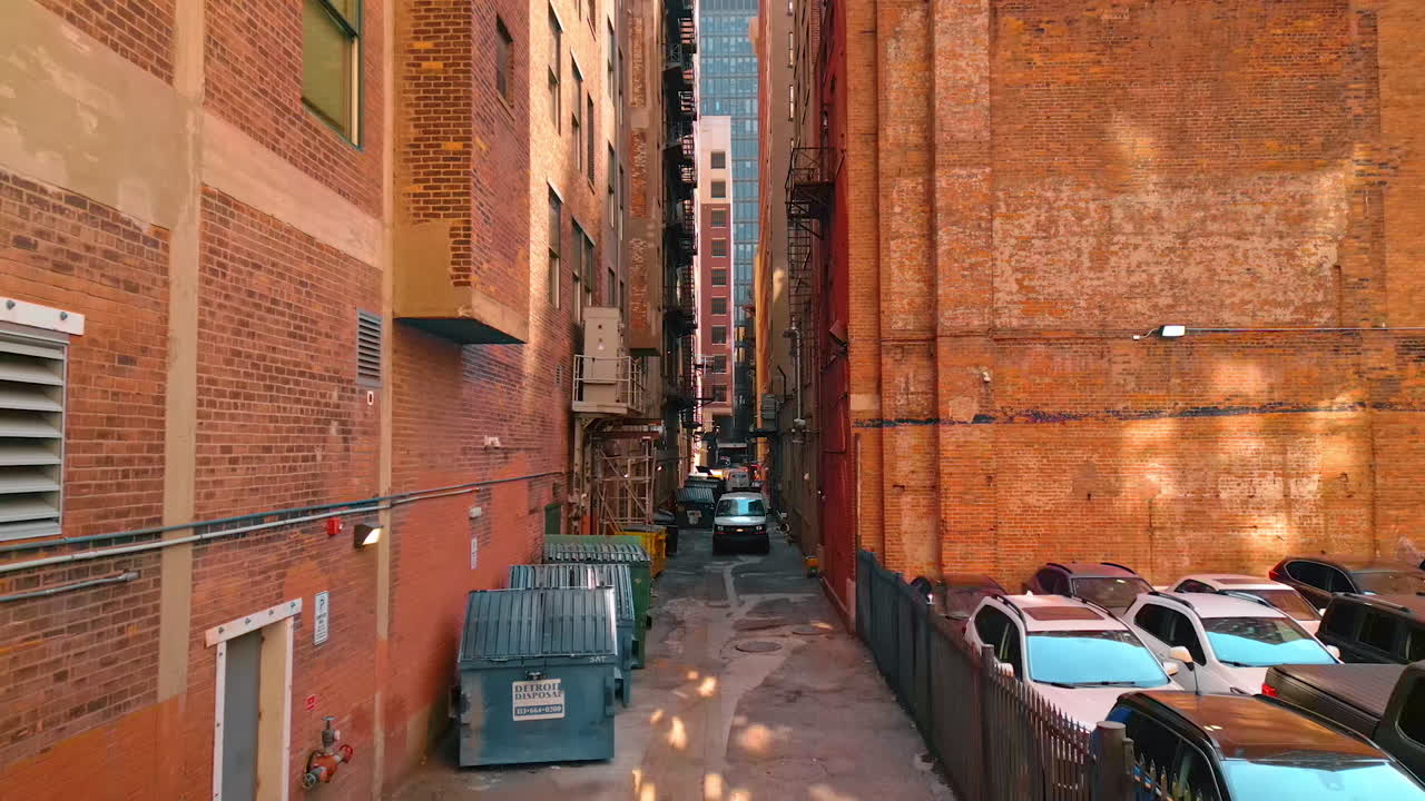 Detroit, USA, 28 July 2025: Narrow street with rubbish containers among the high-rise brick buildings. Drone footage in the downtown of Detroit, Michigan, USA