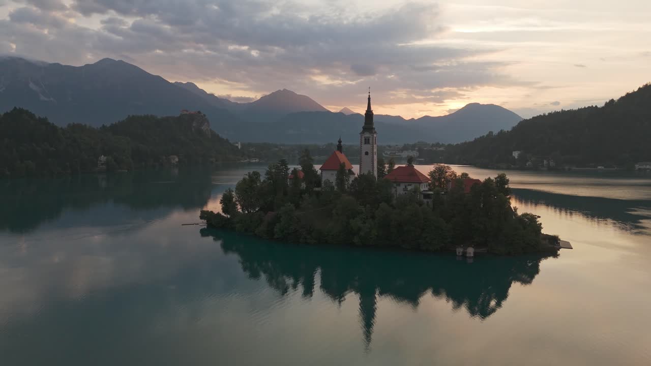 Chiesa su un'isola nel Lago di Bled, Slovenia, durante le ore mattutine, che rivela le montagne.
