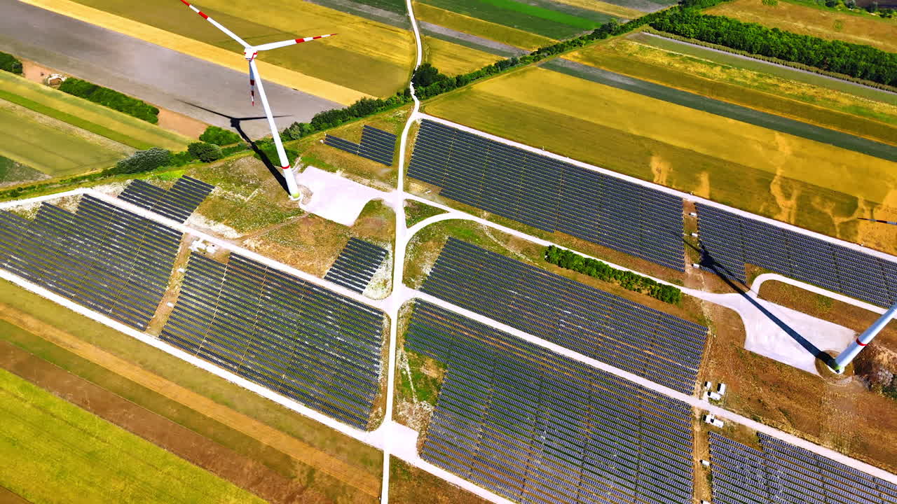 Flight over the fields with solar panels and some wind turbines. Sustainable energy concept