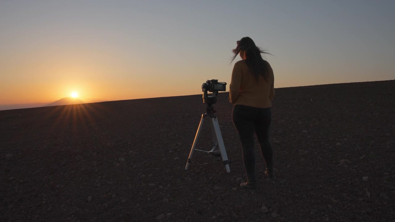 Kvinnelig filmskaper som filmer solnedgang i ørkenen.