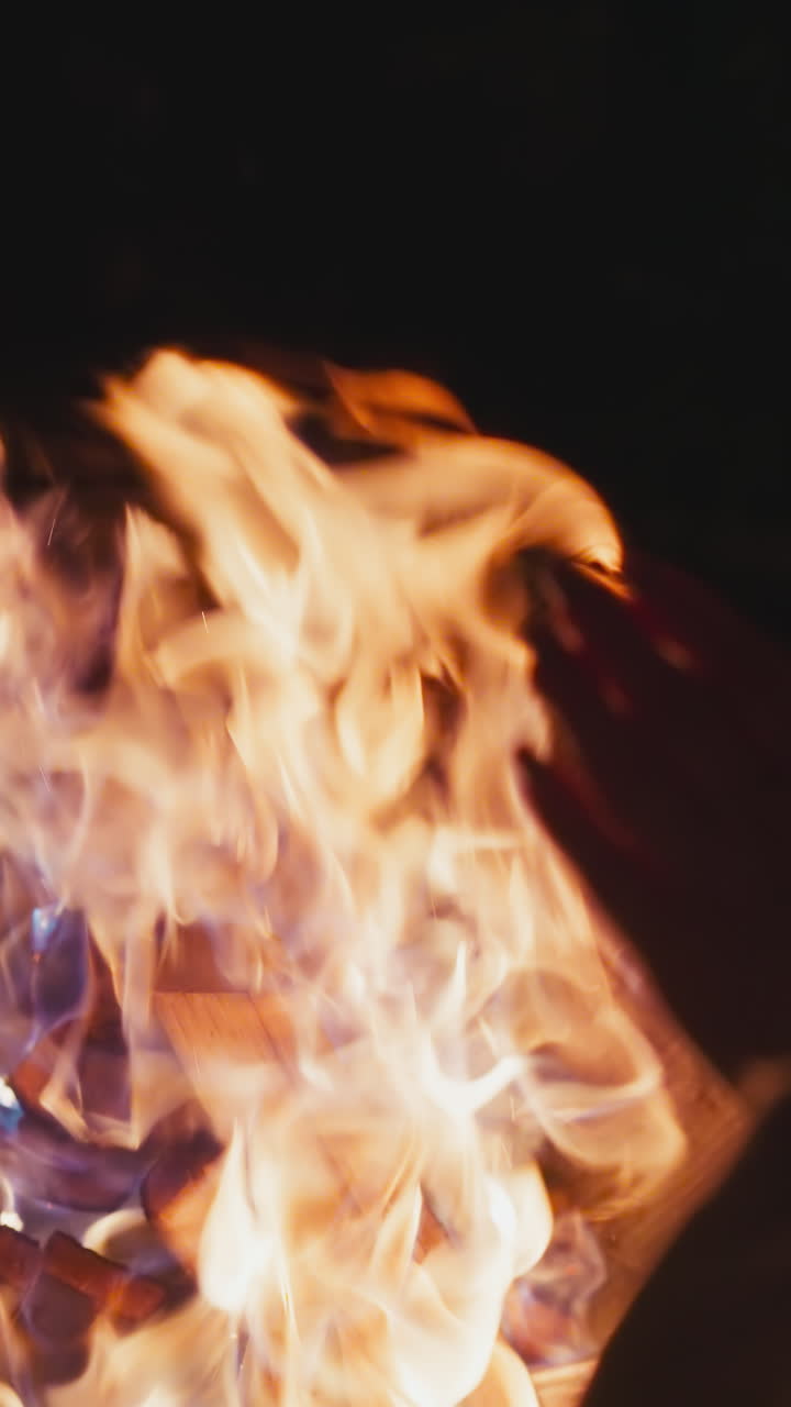dama calienta las manos sobre el fuego ardiente. calentamiento de las extremidades en la fuente caliente por la noche. calma y relajación en el patio de la casa en una atmósfera tranquila
