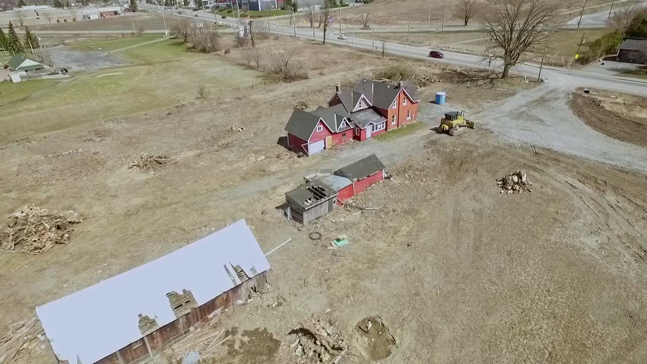 aerial decaying farmhouse near suburbs about to be torn down slow track out