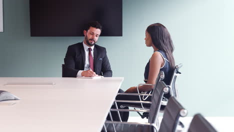 businessman interviewing female candidate at graduate recruitment assessment day in office