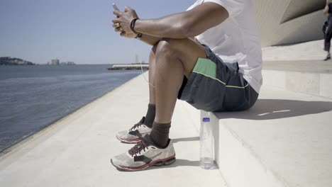 Side-view-of-African-American-man-using-modern-phone-outdoor.