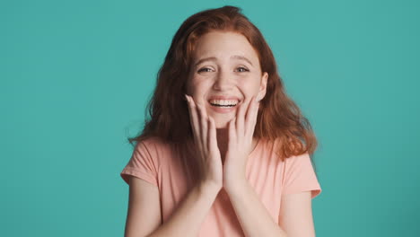 redheaded girl in front of camera on turquoise background.