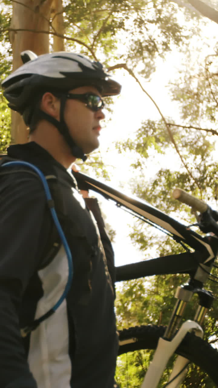 Bicicletta di trasporto del ciclista in mountain-bike maschio nella foresta