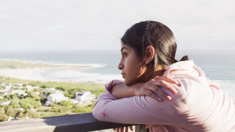 video of thoughtful biracial woman by sea looking into distance