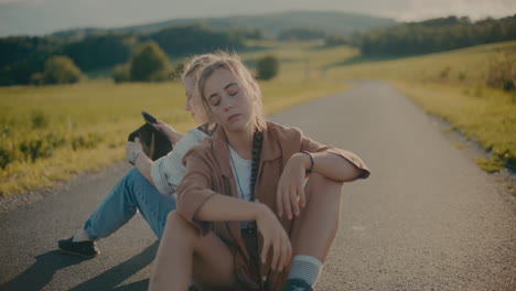 Bored-Female-Tourists-Sitting-Together-On-Road