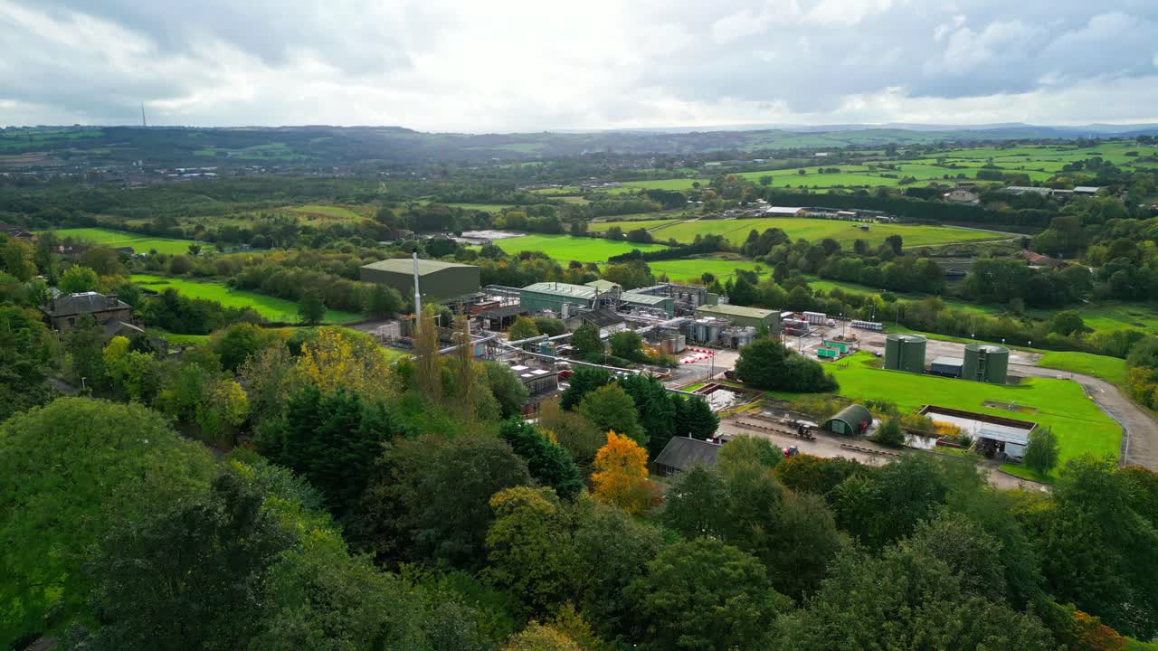 Aerial footage moves closer to a UK chemical factory, highlighting pipes, metal constructions, cooling towers, and chemical storage