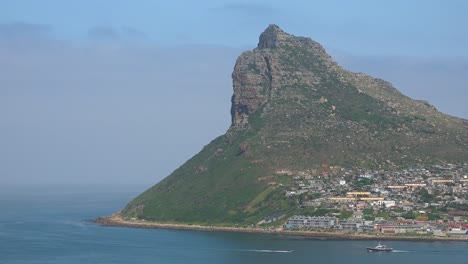 un barco navega a lo largo de los acantilados y montañas en la región del cabo de buena esperanza cerca de ciudad del cabo sudáfrica