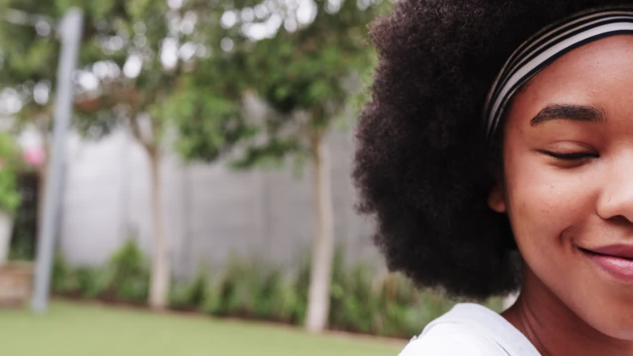 Donna afroamericana sorride ampiamente dopo essere stata inquadrata in giardino, con una fascia per capelli e spazio per il testo.