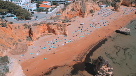 people walking on the beach during the summer in praia dona ana in the algarve in portugal, aerial drone view