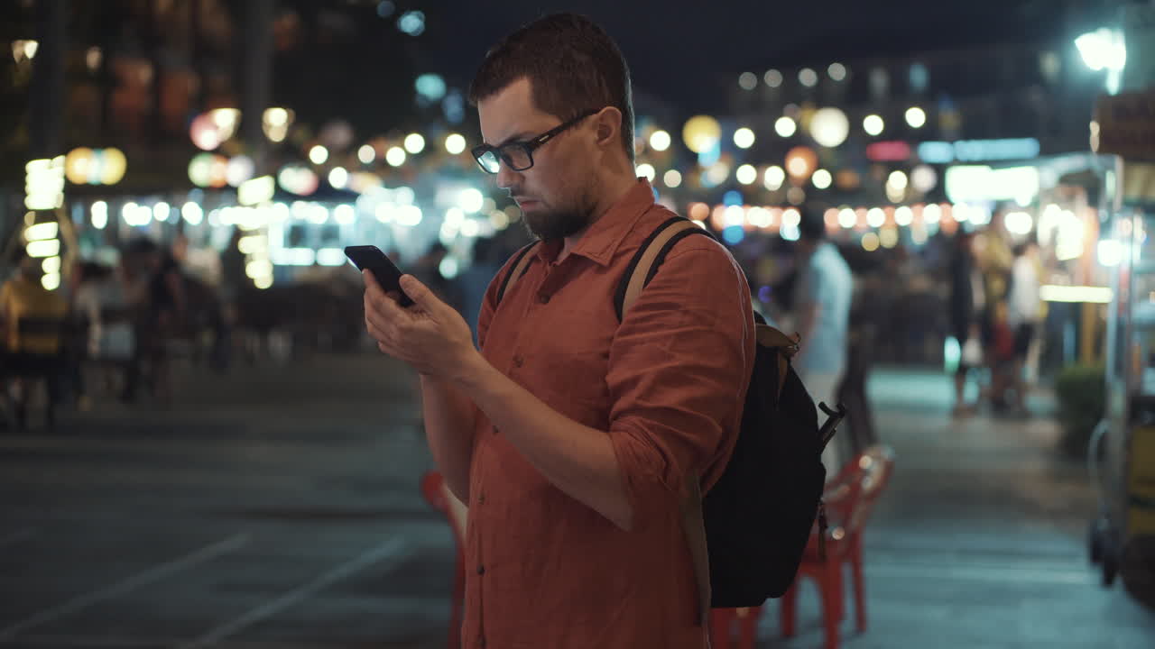 hombre usando el teléfono en un mercado nocturno