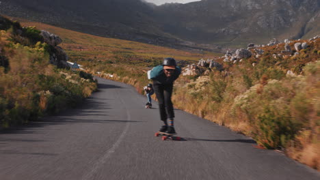 young friends longboarding together cruising on countryside road having fun riding skateboard wearing protective helmet happy teenagers racing