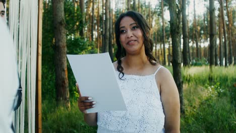 mujer leyendo un documento durante una ceremonia de boda en un bosque