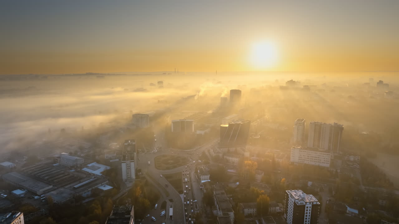Aerial drone timelapse view of Chisinau at sunrise, Moldova. View of the city with fog in the air, multiple buildings, Dendrarium park and streets with yellowed trees