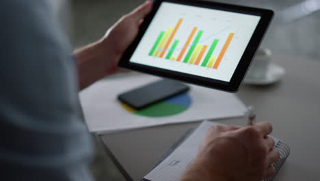 business man researching charts graph using tablet computer pad in remote office