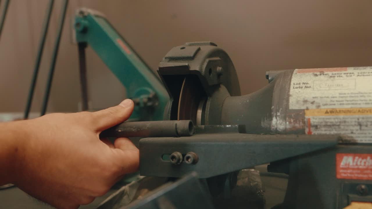Cutting golf shaft with saw machine in slow motion, close up 4k of craftsman club builder's hand in golf workshop