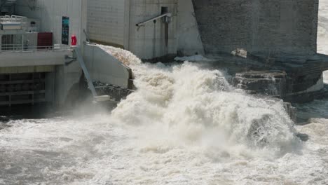 raging river water pouring out of the power generation building of the hydro electric damn on chaudière island and pouring into the ottawa river