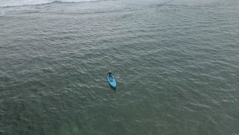 a man kayak in tropical beach - aerial orbit drone shot