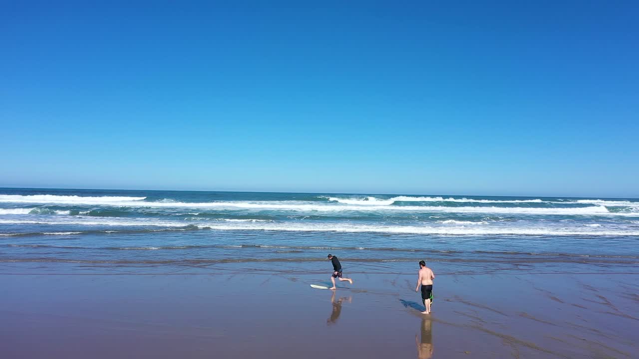 Aerial shot of someone wiping out on a skim board at the ocean
