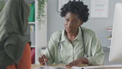 Female-Doctor-Or-Consultant-Having-Meeting-With-Female-Patient-Wearing-Headscarf-To-Discuss-Scans