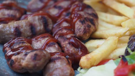 albóndigas a la parrilla con papas fritas y ensalada, salpicadas con salsa