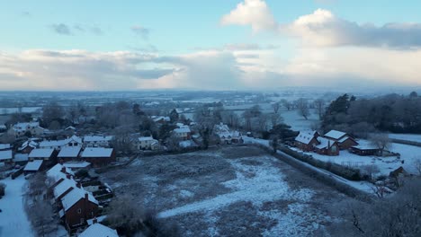 A stunning drone shot of an English village, where warm morning sun meets the crisp white of freshly fallen snow.
