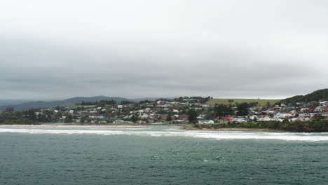 Aerial-drone-shot-flying-over-the-ocean-towards-Gerroa-on-a-stormy-day-in-the-south-coast-of-NSW,-Australia