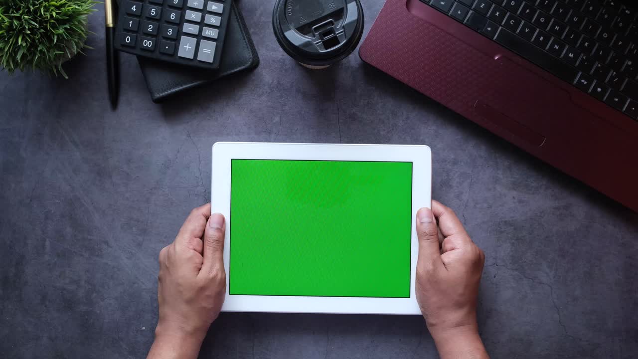 persona que sostiene una tableta con pantalla verde, espacio de trabajo de la oficina