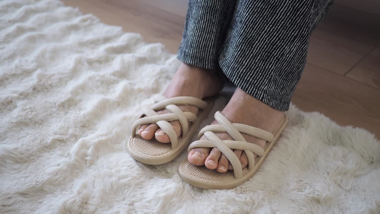 Feet in woven slippers on a white rug