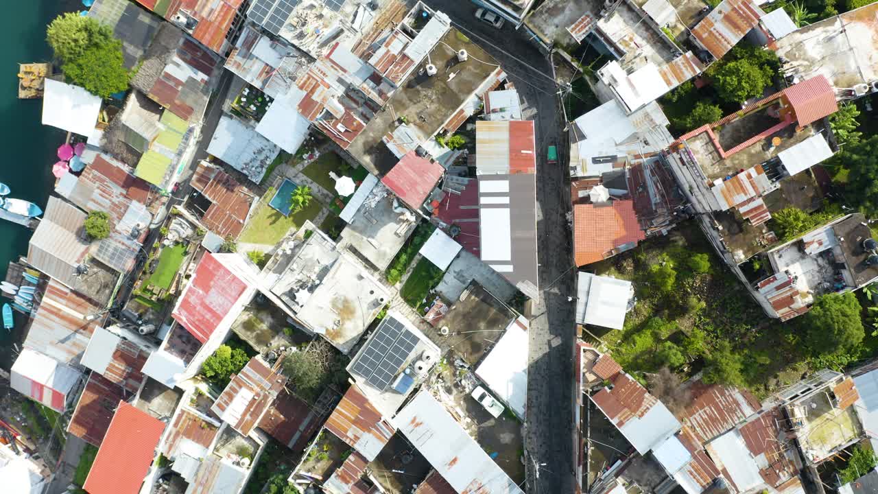 Drone rises above bird's eye view of winding country road near coast of Lake Atitlan Guatemala