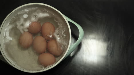 eggs are being cooked in a pot with boiling hot water with some foam on top