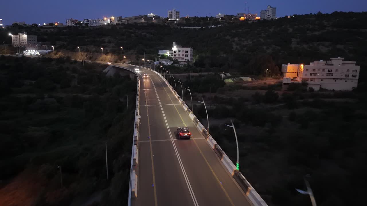 Drone following a car driving on a highway bridge in the outskirts of Al-Baha, SA
