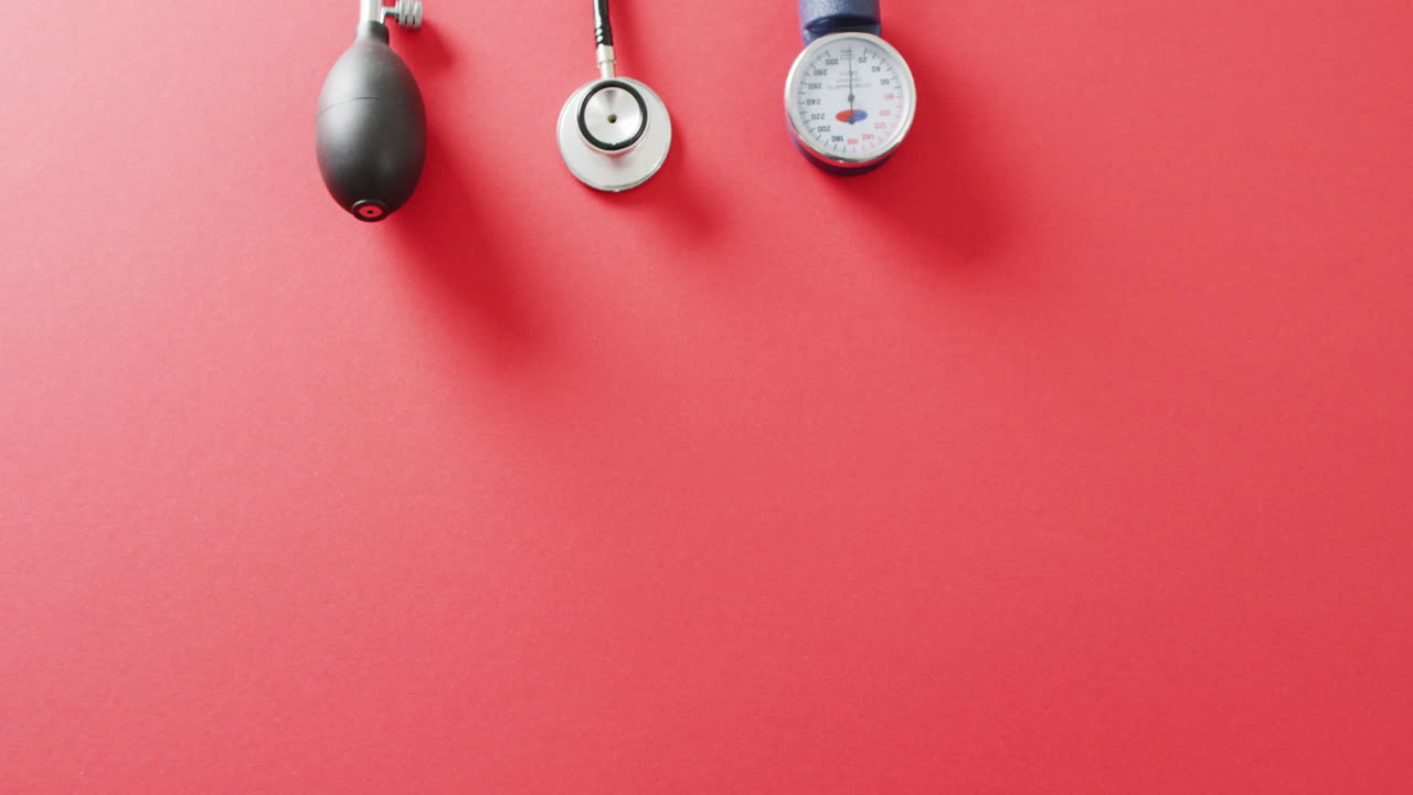 스피그모마노미터를 가진 스테토스코프의 비디오, 복사 공간이 있는 빨간색 배경