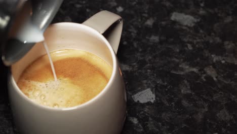 pouring milk into a freshly made coffee