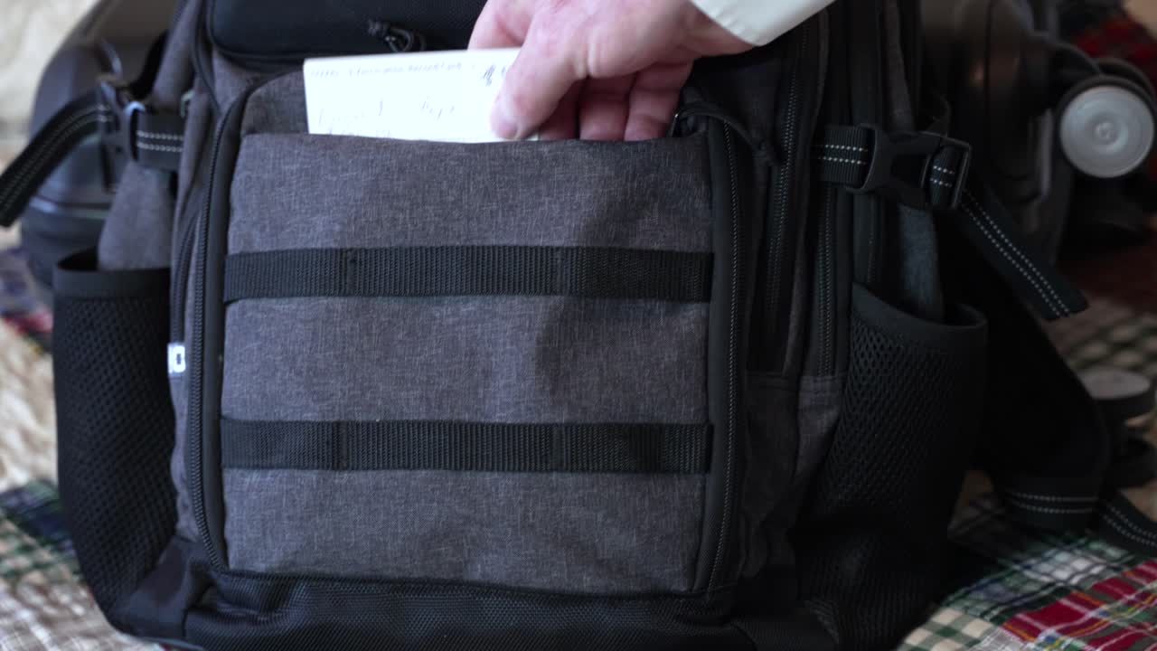 Primo piano: mano di uomo che inserisce la tessera vaccinale COVID nel bagaglio a mano per un viaggio