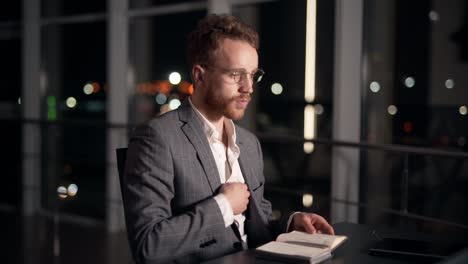 successful young man in a suit receives a joyful message sitting at the table