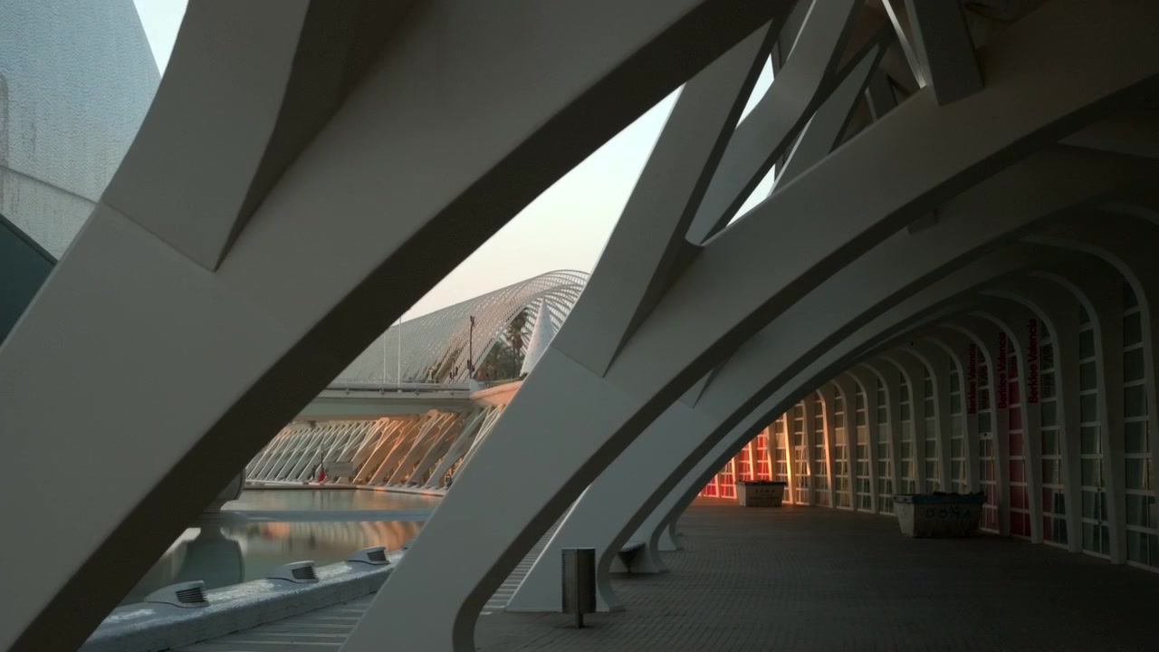 Low-angle view through enclosed modern passage with strong diagonal beams, layered curves, mirrored water edge, and quiet contemporary mood, with architecture, corridor, curved, modern detail