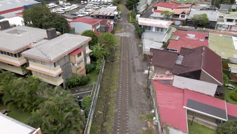 Aerial-shot-flying-over-train-tracks-and-houses-in-San-Jose,-Costa-Rica