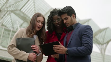 Three-young-people-outside-googling-on-tablet-place-to-go