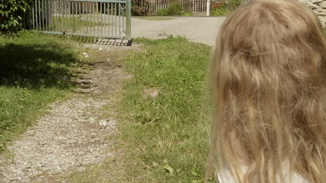 a little girl crouches and stares as white butterflies dance and fly in slow motion