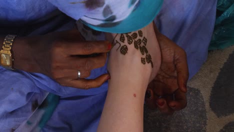 a close up shot of a white woman foot being painted with henna by a black woman