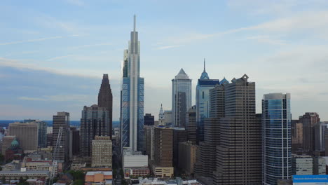 aerial drone flying backward through philadelphia city skyline showcasing comcast technology center and tall east coast skyscrapers and buildings