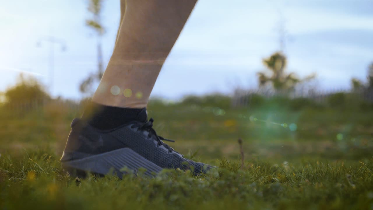 Slow motion close up of person skipping rope on grass field in nature